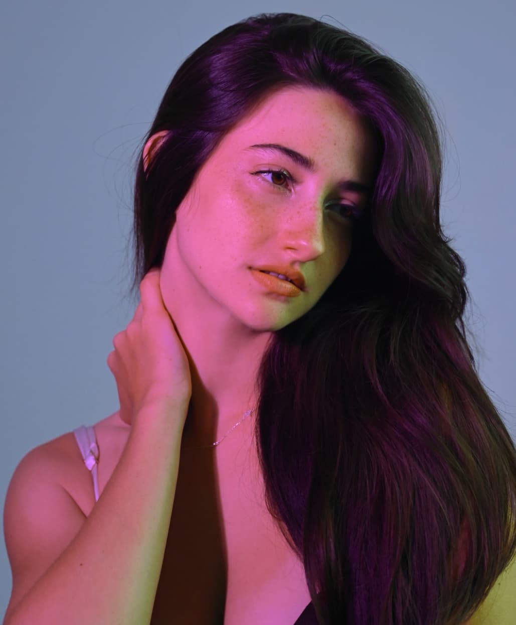 Close-up editorial portrait of Maite Warken lit with pink studio lighting in Florianópolis for Rirod Studio.