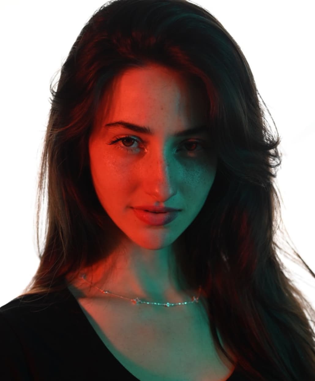 Close-up editorial portrait of Maite Warken lit with red and teal studio lighting in Florianópolis for Rirod Studio.